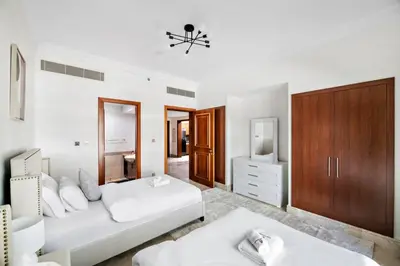 a white bedroom with a bed and a tv at StoneTree - Fairmont North 2 BR - Beach Access in Dubai