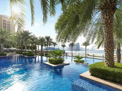 a large swimming pool with palm trees in a resort at StoneTree - Fairmont North 2 BR - Beach Access in Dubai