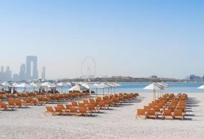 a beach with chairs and umbrellas and the ocean at StoneTree - Fairmont North 2 BR - Beach Access in Dubai