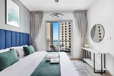 a bedroom with a large white bed and a balcony at StoneTree - Attessa Tower 1BR - Amazing View in Dubai