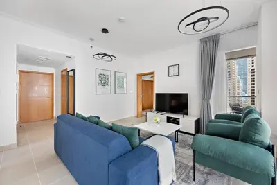 a living room with two blue couches and a tv at StoneTree - Attessa Tower 1BR - Amazing View in Dubai