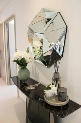 a mirror on a table with flowers in a vase at Burj Royale Residences Downtown Dubai - Burj Khalifa District in Dubai
