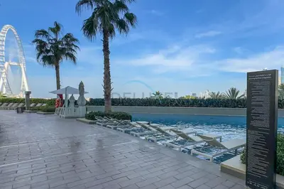 a swimming pool with lounge chairs and a ferris wheel at Stylish 1BR in Prime Location, Book Your Stay by Deluxe Holiday Homes in Dubai