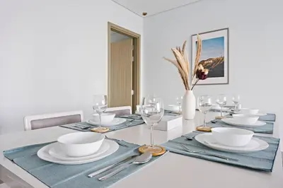 a dining room table with plates and glasses and a vase at StoneTree - Paramount 3 BR - Infinity Pool in Dubai