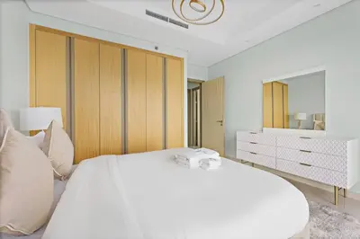 a white bedroom with a large white bed and a dresser at StoneTree - Paramount 3 BR - Infinity Pool in Dubai