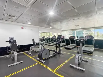 a gym with rows of tread machines in a room at StoneTree - Marina Pinnacle 1 BR - Partial Marina View in Dubai