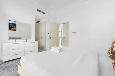 a white bedroom with a white bed and a tv at StoneTree - Pelham Villa 3 BR - Damac Hills in Dubai