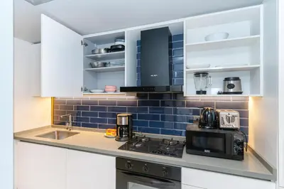 a kitchen with white cabinets and a black microwave at MAG 318 Studio Walk to Dubai Mall in Dubai