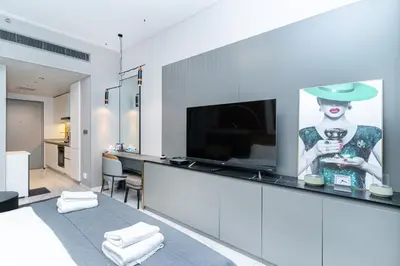 a living room with a television and a painting of a woman at MAG 318 Studio Walk to Dubai Mall in Dubai