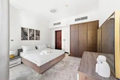 a bedroom with a large bed and a wooden cabinet at StoneTree - Indigo Tower 1BR - Panoramic View in Dubai