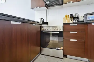 a kitchen with wooden cabinets and a stainless steel oven at Stylish Sports City Studio Golf View PoolGym in Dubai