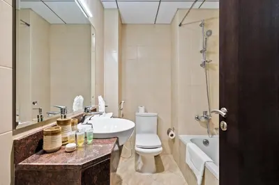 a bathroom with a toilet and a sink and a tub at Stylish Sports City Studio Golf View PoolGym in Dubai