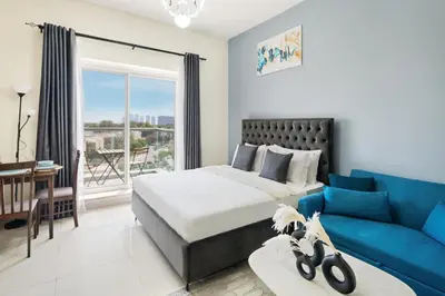 a bedroom with a bed and a blue couch at Stylish Sports City Studio Golf View PoolGym in Dubai