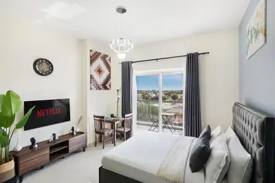 a bedroom with a bed and a view of a balcony at Stylish Sports City Studio Golf View PoolGym in Dubai