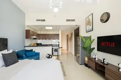 a bedroom with a large bed and a kitchen at Stylish Sports City Studio Golf View PoolGym in Dubai
