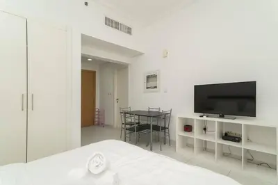 a white bedroom with a television and a table at StoneTree - Elegant Studio in Business Bay in Dubai