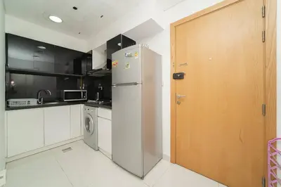 a kitchen with a refrigerator and a wooden door at StoneTree - Elegant Studio in Business Bay in Dubai