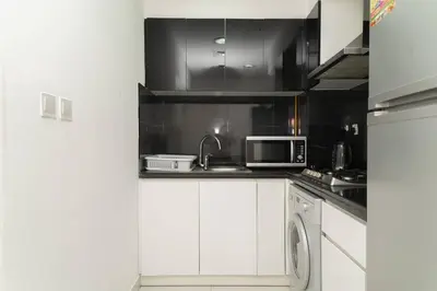 a kitchen with white cabinets and a microwave at StoneTree - Elegant Studio in Business Bay in Dubai