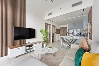 a living room with a couch and a tv on a wall at WelHome - Contemporary 1BR in Binghatti Canal & Burj Views in Dubai