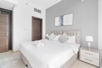 a white bedroom with a large bed with white sheets at StoneTree - Modern 1BR near Dubai Marina Mall in Dubai