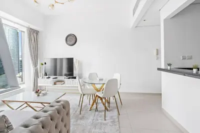 a white living room with a table and chairs at StoneTree - Modern 1BR near Dubai Marina Mall in Dubai