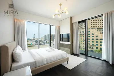 a bedroom with a large bed and a large window at Mira Holiday Homes - Newly 1 bedroom with pool access in Dubai