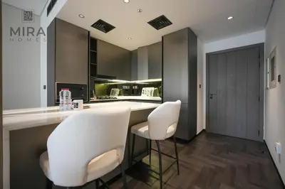 a kitchen with two white chairs at a counter at Mira Holiday Homes - Newly 1 bedroom with pool access in Dubai