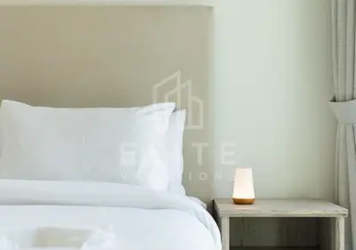a bed with white sheets and a candle on a table at Walk to Dubai Mall 2 Bed Full Burj Khalifa Views in Dubai