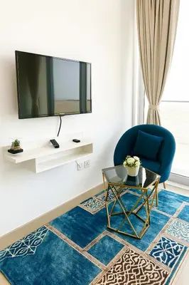 a living room with a blue chair and a tv at Luxurious & Modern Studio in JVC in Dubai