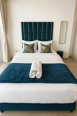 a bed with a towel laying on top of it at Luxurious & Modern Studio in JVC in Dubai