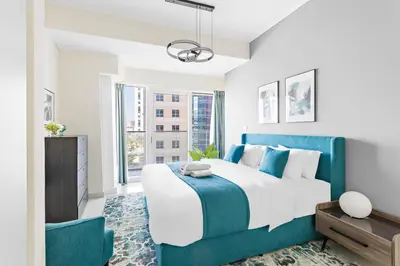 a bedroom with a blue and white bed and windows at StoneTree - Damac Heights 1BR apartment in Dubai