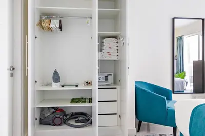 a bedroom with a blue chair and a mirror at StoneTree - Damac Heights 1BR apartment in Dubai