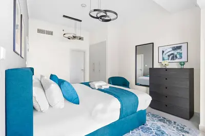 a bedroom with a large bed with blue pillows at StoneTree - Damac Heights 1BR apartment in Dubai