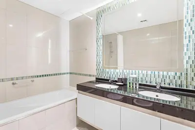 a bathroom with two sinks and a tub and a mirror at StoneTree - Damac Heights 1BR apartment in Dubai