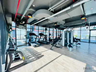 a gym with cardio equipment in a building with windows at Timeless 1BR at Binghatti Avenue Al Jaddaf by Deluxe Holiday Homes in Dubai