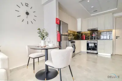 a kitchen with a table and chairs and a clock on the wall at Timeless 1BR at Binghatti Avenue Al Jaddaf by Deluxe Holiday Homes in Dubai
