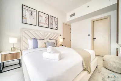 a white bedroom with a large bed and a chair at Soothing 1BR at Binghatti Avenue Al Jaddaf by Deluxe Holiday Homes in Dubai