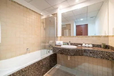 a bathroom with a sink and a tub and a mirror at StoneTree - Spacious 2 BR near JBR beach in Dubai