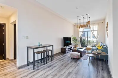 a living room with a blue couch and a table at ALiving Elegant & Cozy 1BR I Mazaya 11, Liwan in Dubai