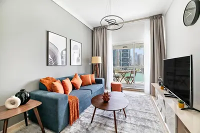 a living room with a blue couch and a tv at StoneTree - 1BR apartment with Lake View in Dubai