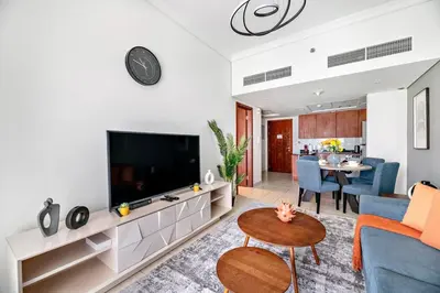 a living room with a tv and a couch and a table at StoneTree - 1BR apartment with Lake View in Dubai