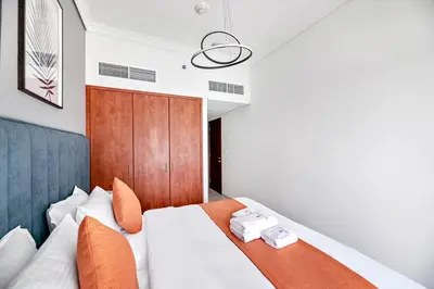 a bedroom with a white bed with a wooden headboard at StoneTree - 1BR apartment with Lake View in Dubai