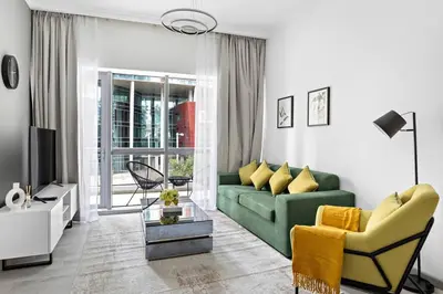 a living room with a green couch and a tv at StoneTree - Stylish Apartment with amazing building facilities in Dubai