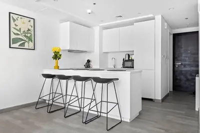 a kitchen with white cabinets and a counter with stools at StoneTree - Stylish Apartment with amazing building facilities in Dubai
