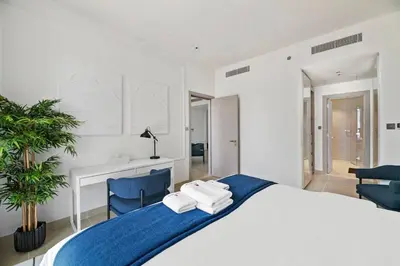 a white bedroom with a large bed and two blue chairs at StoneTree - Modern Living in Dubai Marina in Dubai