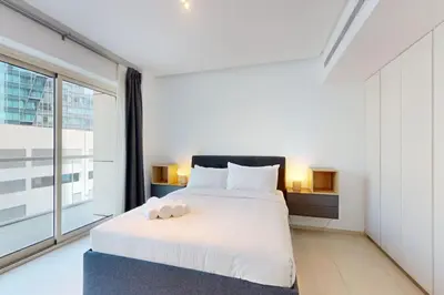a bedroom with a white bed and a large window at West Avenue - Chic One Bedroom in Dubai