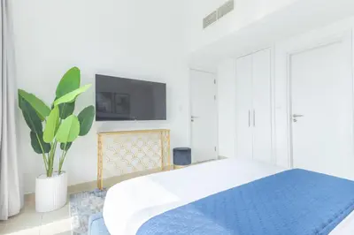 a white bedroom with a bed and a tv at Frank Porter - Bay Central 1 in Dubai