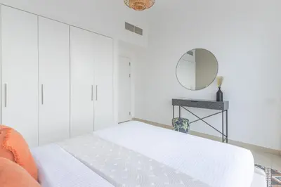 a white bedroom with a bed and a mirror at Frank Porter - Bay Central 1 in Dubai