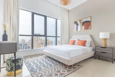 a white bedroom with a bed and a large window at Frank Porter - Bay Central 1 in Dubai