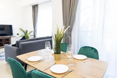 a wooden table with plates and wine glasses on it at Bahar JBR Apartment by HAPPY SEASON in Dubai
